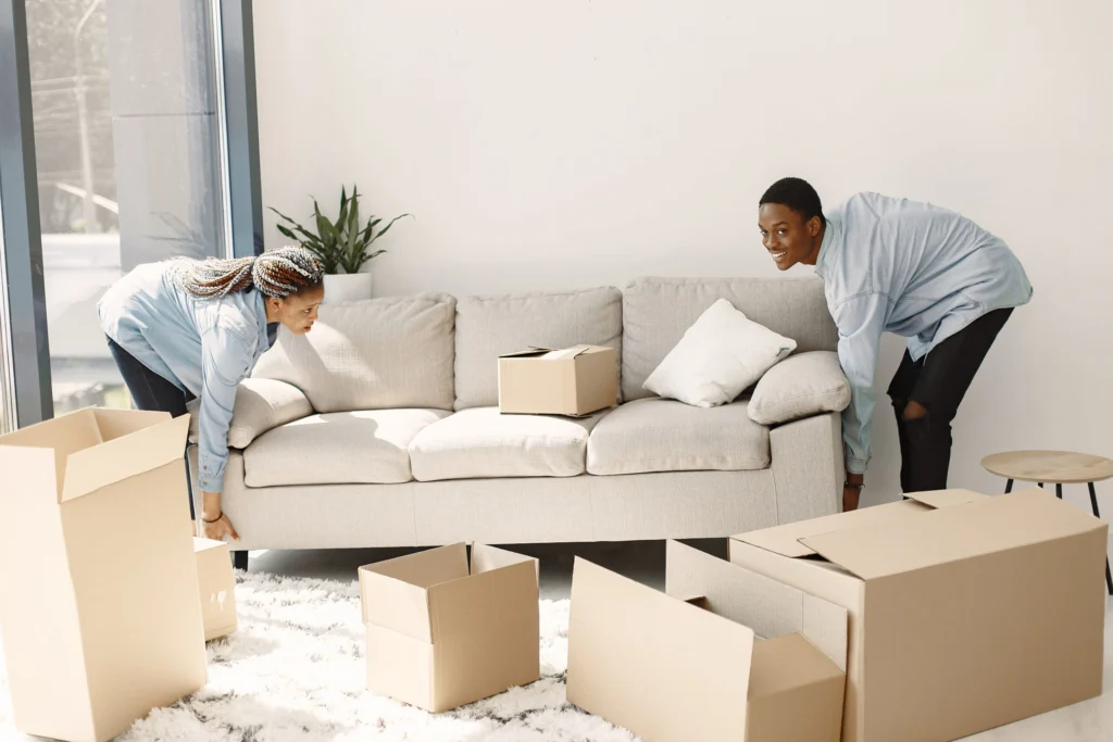 Young couple moving with cardboard boxes, Upper 90 Solutions junk hauling and moving service.